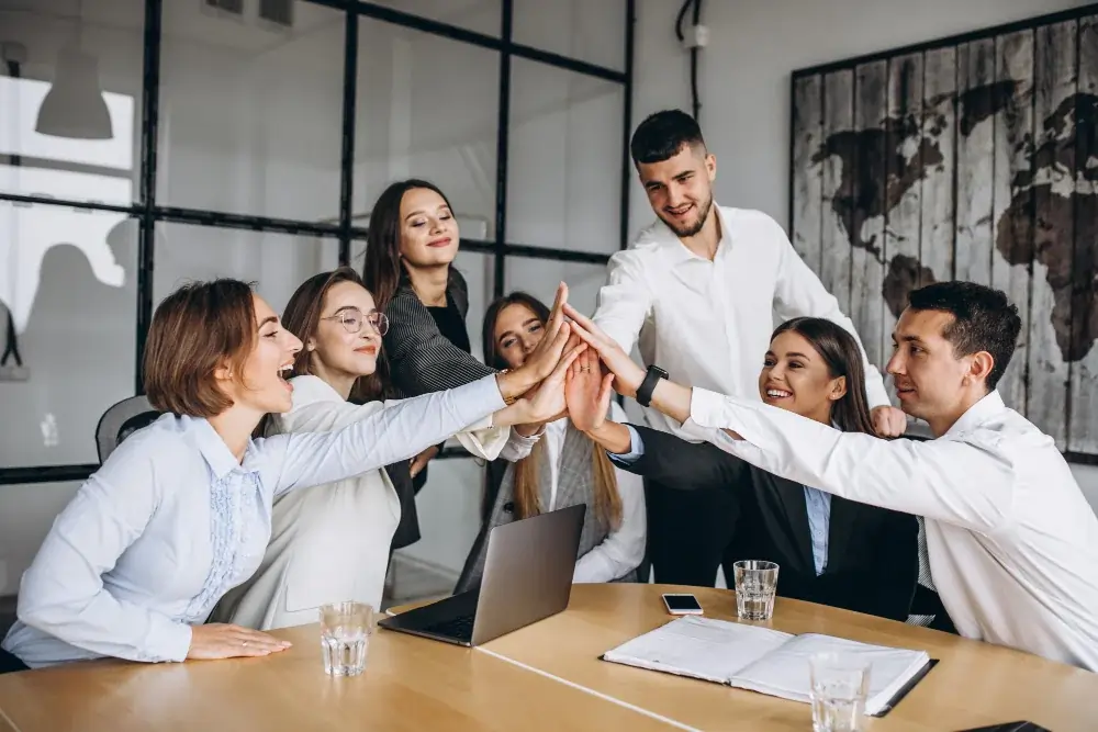 Join Our Dedicated Team at Highbridge care solutions in UK A group of professionals in business attire celebrate teamwork with a high-five, symbolizing unity and success.